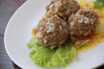 Homemade meatballs with rice and carrots in vegetable sauce with lettuce