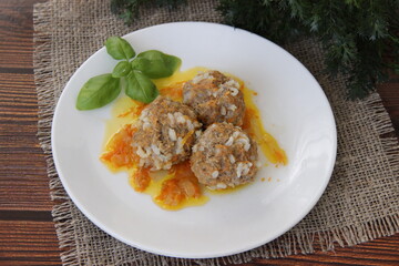 Meatballs with rice and carrots on a white plate and dark wooden boards