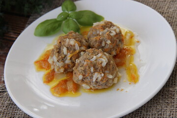 Homemade meatballs with rice and carrots in vegetable sauce with lettuce