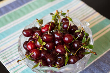 Shaped vase with ripe maroon cherries on a textile striped napkin...