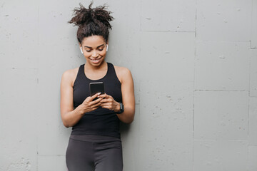 Gadgets and devices for sport. Girl with headphones from smart watch looks at smartphone