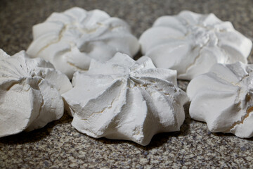 Off white marshmallow roses on a spotty surface. Delicious homemade meringue cakes. The concept of home cooking of food.