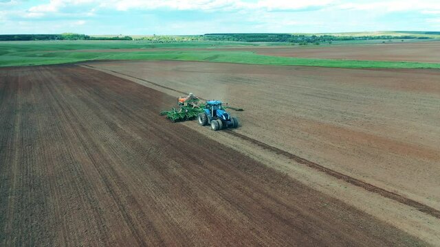 Tractor is riding along the field and sowing it