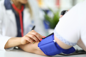 Woman doctor measures pressure to patient in medical office. Heart disease examination and prevention treatment concept