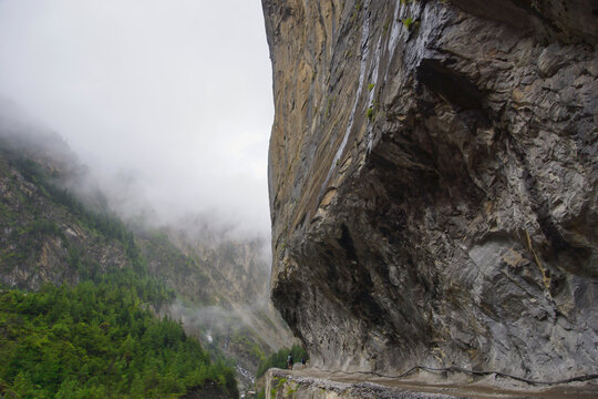 Vehicle road from Besisahar to Manang. New road, on the Annapurna circuit, blasted into a step cliff next to Marsyangdi river. Hikers highlight the impressive cliff.