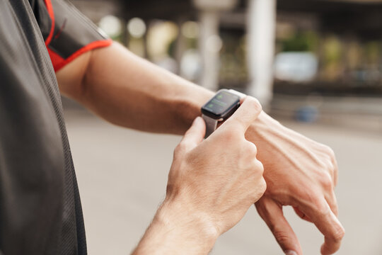 Cropped image of athletic sportsman using smartwatch while working out