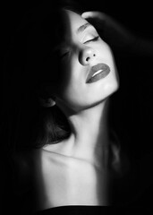 Dramatic model portrait. Woman's Face with Sexy Red Lips. Shadows. Secrecy. Black and white.