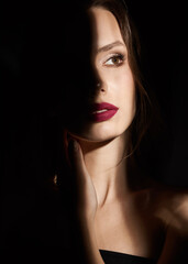 Dramatic model portrait. Woman's Face with Sexy Red Lips and beautiful modern makeup. Shadows. Secrecy