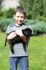 Uśmiechnięty chłopiec trzyma na rękach czarnego szczeniaka labrador retriever © Joanna