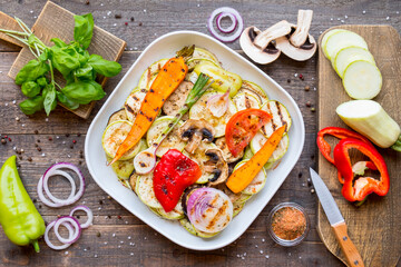 Top view of assorted grilled vegetables on plate on wooden background