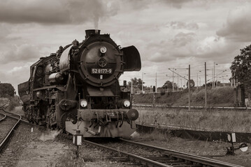 Naklejka premium Lokomotywa parowa, niemiecka lokomotywa parowa, lokomotywa parowa i duże chmury w tle, czarno-białe zdjęcie