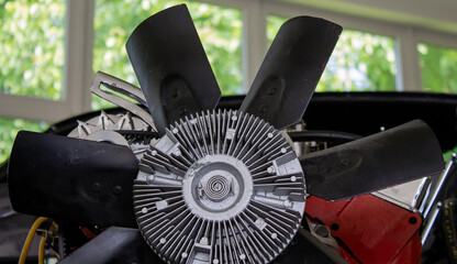 Fan wheel of a V8 engine built into a body shell of a muscle car. Taken close up.