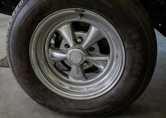 Photo of a muscle car to be restored. The tire and the original rim are included.