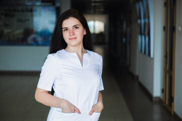 Medical student smiling at camera in university in a white surgical suit. professional girl surgeon doctor.