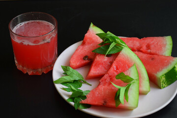 Refreshing watermelon smoothie and bowl of watermelon on dark background