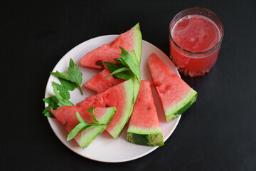 Refreshing watermelon smoothie and bowl of watermelon on dark background