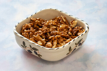 Bowl with tasty walnuts on light table