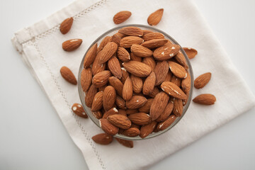 Almond in a bowl on white serviette. White background, view from above
