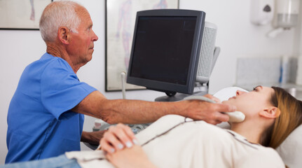 Obraz premium Mature male doctor using ultrasound scan examining female patient in modern hospital