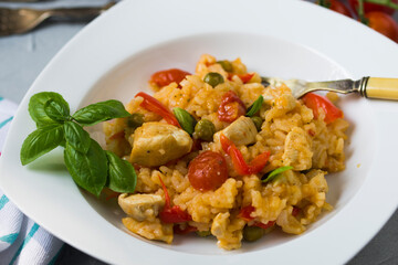 Paella with chicken breast, red pepper and cocktail tomatoes.