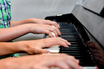 Brother and sister play the piano with four hands. Children learn the art of music. © andov