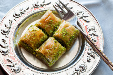 Baklava with walnut and pistachio. Turkish dessert baklava with pistachio and traditional silver serving set. Festival of sacrifices. Ramadan holiday. 