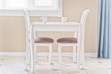 Table, two chairs and two cups of coffee in a bright, clear room