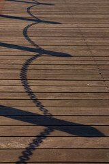 Obraz premium Shadow of chain fence on the old wood bridge.