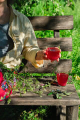 Woman sitting on bench in garden drinking red berries juice