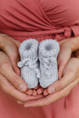 Mother and father (man and woman) are holding hand-knitted baby booties