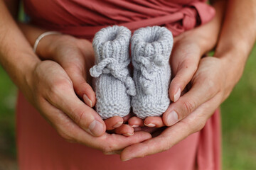 Mother and father (man and woman) are holding hand-knitted baby booties
