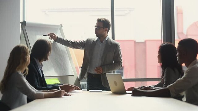 Serious professional conference speaker coach presenter give flip chart business presentation teaching diverse employees group explain team course at office meeting workshop lecture training concept