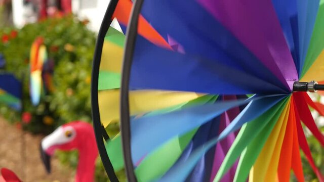 Colorful pinwheel spinning, weather wind vane, garden decoration in USA. Rainbow symbol of childhood, fantasy and imagination rotating. Multi colored spiral toy turning in breeze. Summertime dreaming.