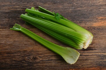 Bunch of fresh celery stalk with leaves on old wooden background