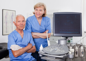 Portrait of qualified male and female doctors near modern ultrasound machine in a medical center