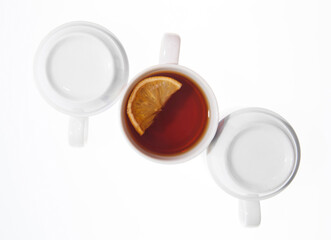 Cup with tea and lemon and emty inverted cups isolated on white background
