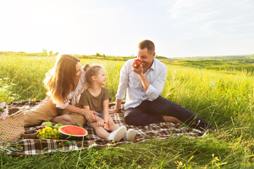 Happy family playing with fruits on a picnic outdoors
