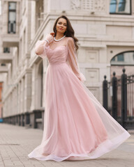 Young beautiful woman wearing long pink dress. Outdoor fashion full length portrait.