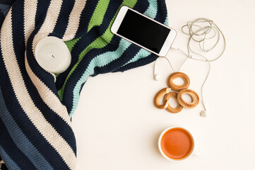 Close up, flat lay, top view. Autumn mood in the office. Warm sweater, orange tea, telephone with headphones. White background.
