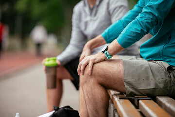 Fit young men taking rest from running. Two friends training outdoors.	