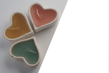 image with white part and photo of three candles with colored wax in the shape of a heart