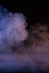 Conceptual image of multi-colored smoke isolated on dark black background and wooden table.