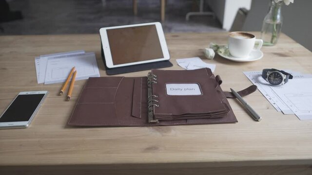 Beautiful close up view on business work area desktop with tablet cell phone coffee mug watch leather note pad