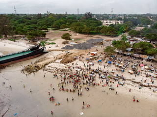 Obraz premium An aerial shot from Bagamoyo, Tanzania. Indian Ocean Coast with Vessels and Crowd of people Carrying Catch from fishermans boats at Low Tide