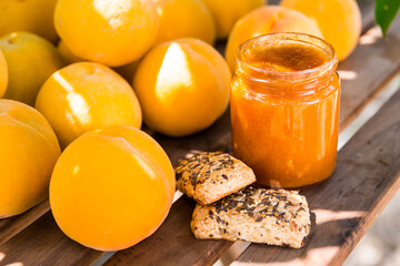 ripe appetizing yellow peaches and marmalade on table in garden