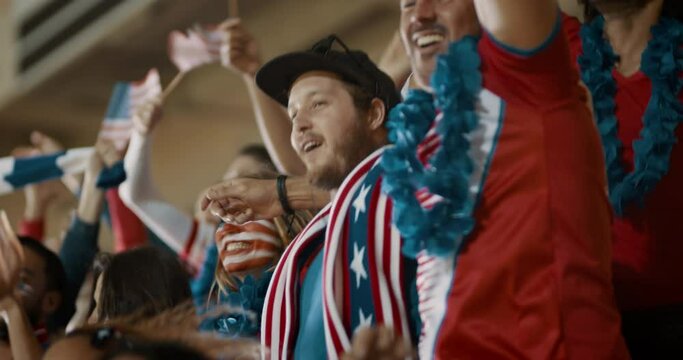 Excited fans celebrating in stands. American soccer supporters cheering over a goal in stadium.
