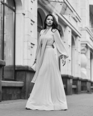 Obraz premium Fashion outdoor portrait. Young stylish woman in long pink evening dress walking at city street on a summer day. Full length