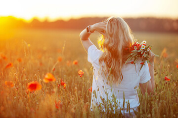 Pretty woman with long hair on poppy field at sunset. Back view. Fashion outdoor photo of beautiful  flying blonde  hair. Close up picture