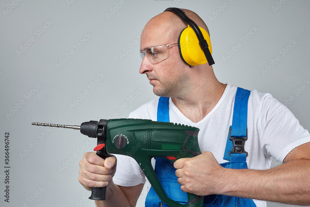 Wall mural grown man with a drill in his hands. the concept of the construction