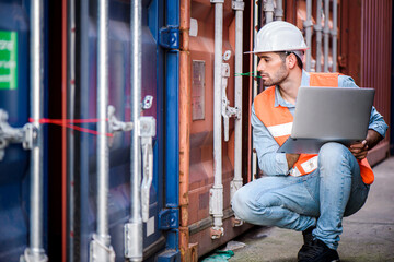 Fototapeta na wymiar Young confident Caucasian man engineer using laptop computer and wearing white safety helmet and check for control loading containers box from Cargo freight ship for import and export, transport